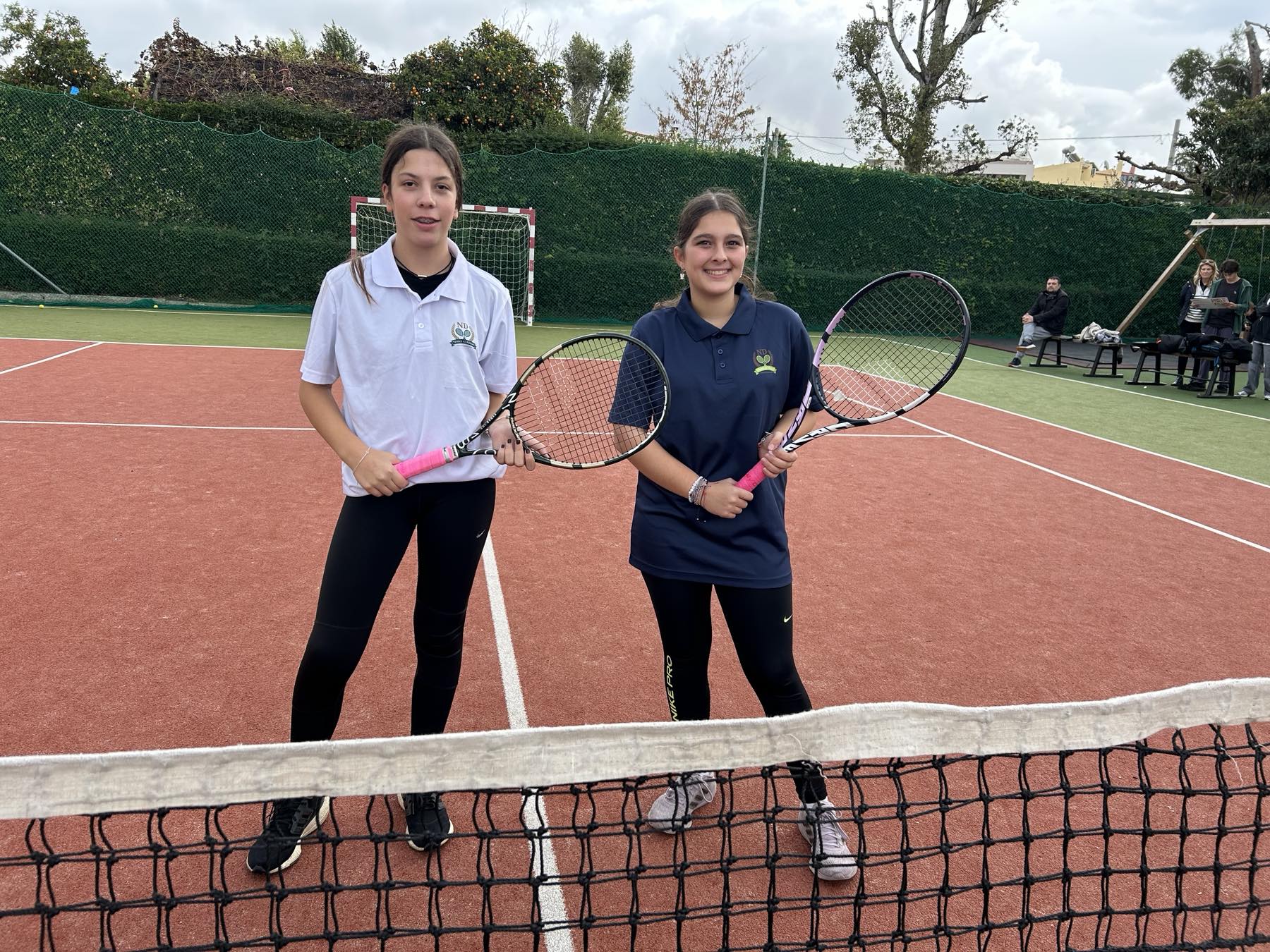 tennis students two girls holding tennis equipment at kids group service